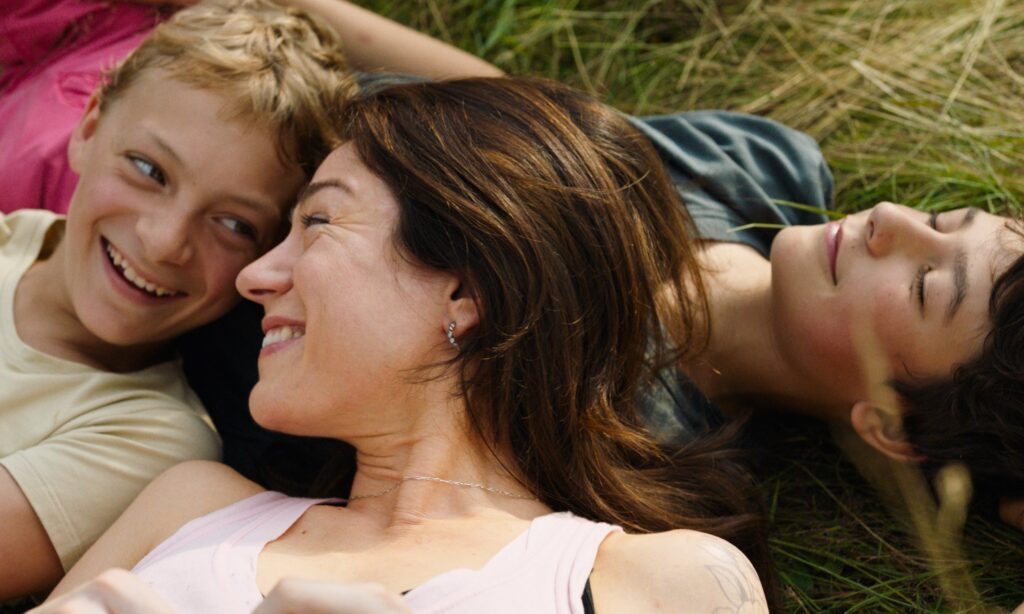 Beeld uit Close: twee jongens en een vrouw in het gras