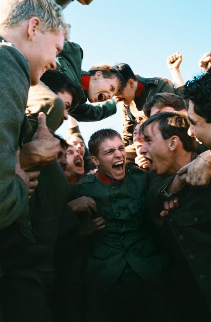 Filmbeeld uit COWARD: soldaten tillen een kameraad lachend op
