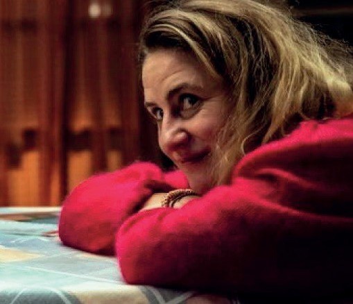 Een vrouw in een rode trui aan tafel, beeld uit J'aime la vie