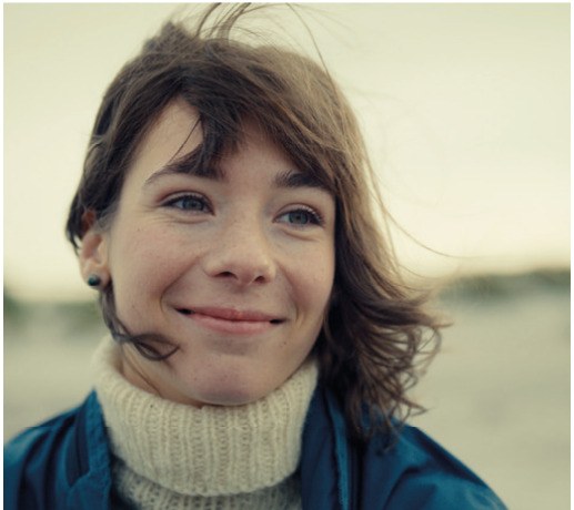 Een lachende jonge vrouw in de wind, beeld uit State of Happiness